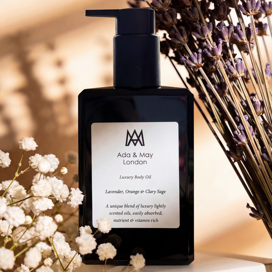 Black bottle of ada and may body oil with lavender flowers and baby's breath on a warm-toned background